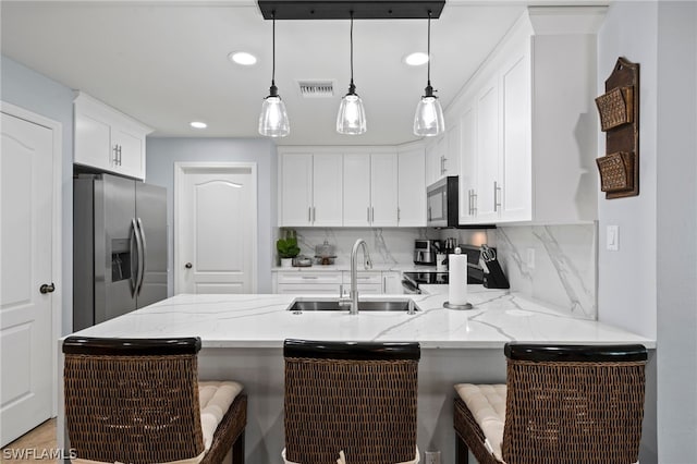 kitchen with appliances with stainless steel finishes, pendant lighting, a kitchen breakfast bar, and sink