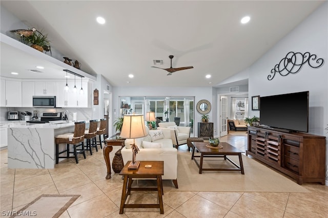 tiled living room featuring ceiling fan, sink, and vaulted ceiling