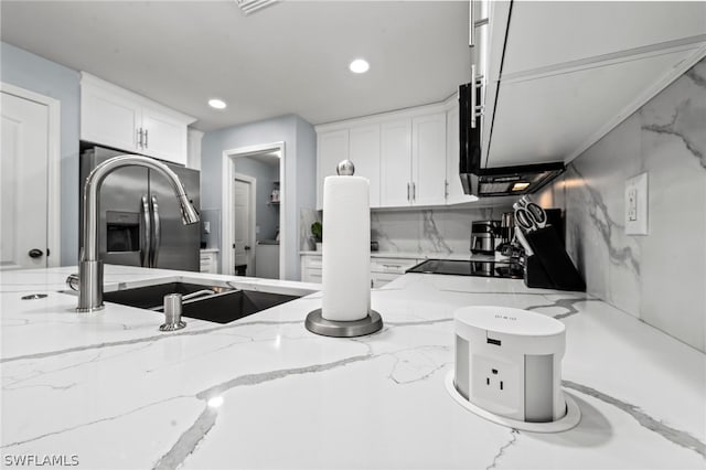 interior space featuring white cabinets, stainless steel fridge, tasteful backsplash, and light stone countertops