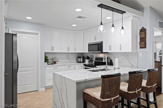 kitchen featuring kitchen peninsula, appliances with stainless steel finishes, light stone counters, pendant lighting, and a breakfast bar area