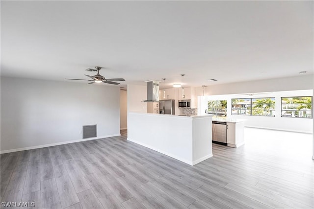 kitchen with light countertops, appliances with stainless steel finishes, island exhaust hood, visible vents, and light wood-style floors