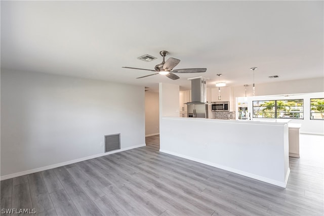 kitchen featuring white cabinets, appliances with stainless steel finishes, ceiling fan, and light wood-type flooring