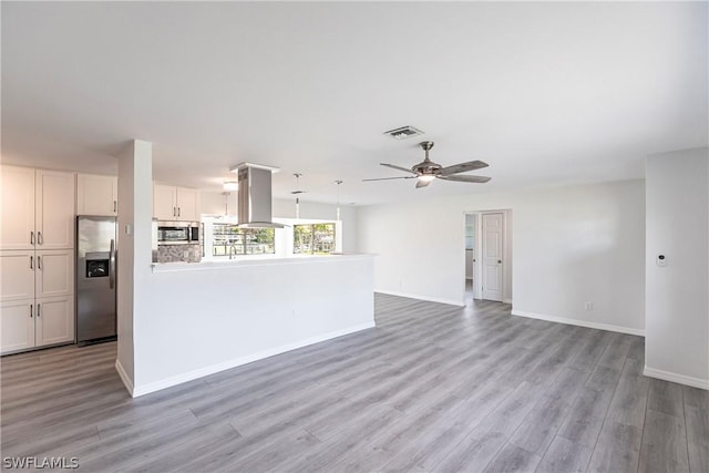 unfurnished living room with baseboards, visible vents, light wood-style floors, and a ceiling fan