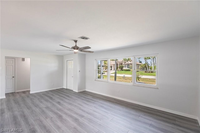 spare room with wood finished floors, visible vents, baseboards, and ceiling fan