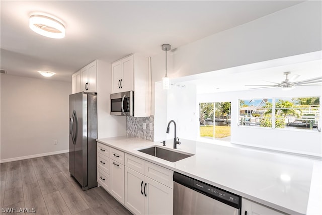 kitchen featuring decorative light fixtures, white cabinetry, ceiling fan, appliances with stainless steel finishes, and sink