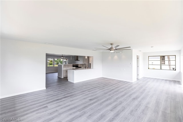 unfurnished living room with ceiling fan, light wood-type flooring, and sink