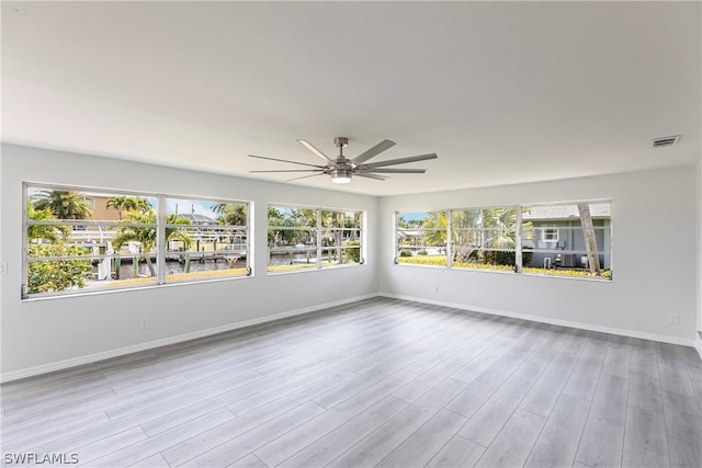 empty room with ceiling fan, a wealth of natural light, and light hardwood / wood-style flooring