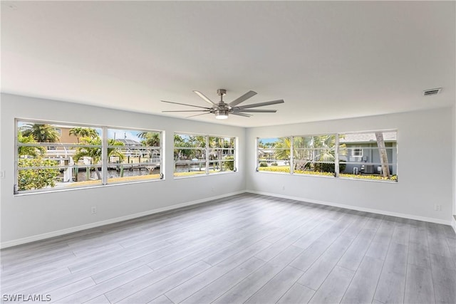 unfurnished room with wood finished floors, baseboards, a healthy amount of sunlight, and ceiling fan