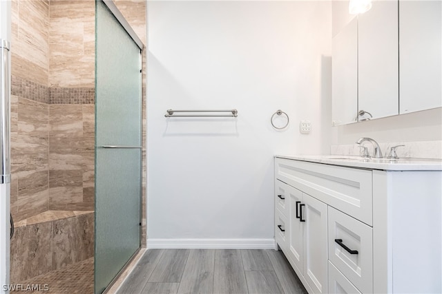 bathroom featuring a shower with door, vanity with extensive cabinet space, and wood-type flooring