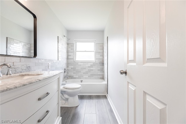 full bathroom featuring tiled shower / bath combo, vanity, wood-type flooring, toilet, and tasteful backsplash