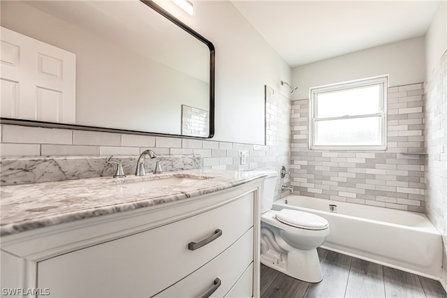 full bathroom featuring tiled shower / bath, toilet, hardwood / wood-style floors, and vanity