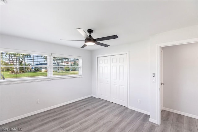 unfurnished bedroom featuring baseboards, a closet, light wood-style floors, and ceiling fan
