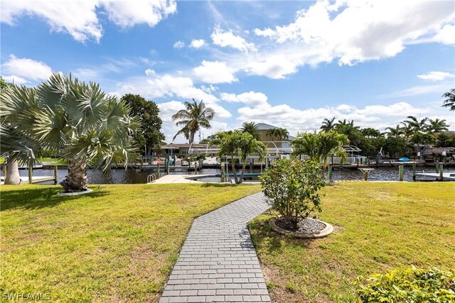 view of property's community with a lawn, a water view, and a dock