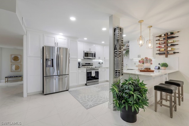 kitchen featuring white cabinets, hanging light fixtures, tasteful backsplash, and stainless steel appliances