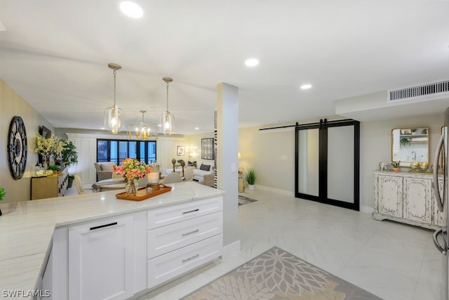 kitchen featuring pendant lighting, light tile floors, light stone counters, white cabinets, and a barn door