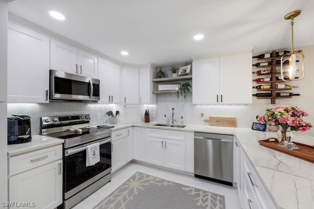 kitchen featuring sink, white cabinets, backsplash, stainless steel appliances, and light tile flooring