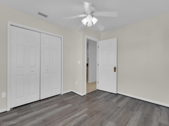 unfurnished bedroom with a closet, dark wood-type flooring, and ceiling fan