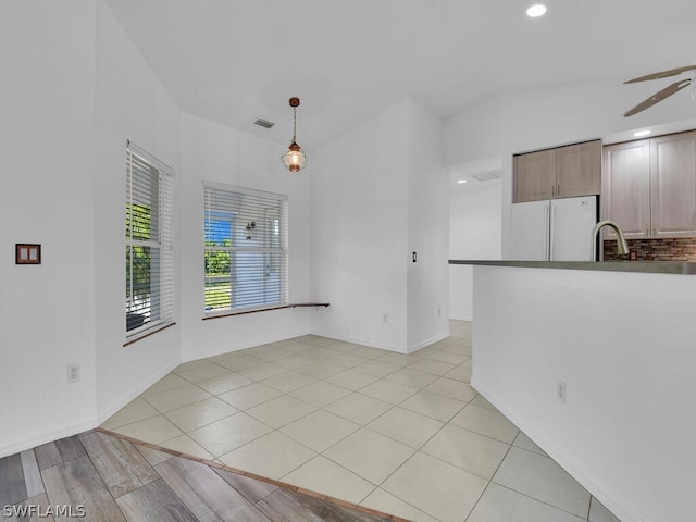 unfurnished living room with sink, ceiling fan, and light tile floors