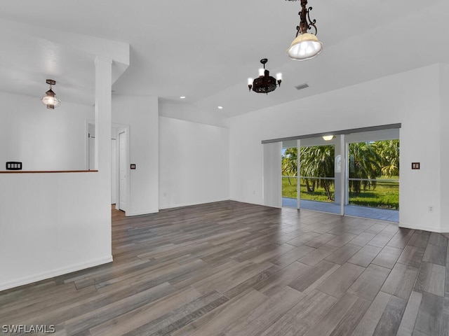 empty room featuring dark wood-type flooring and a notable chandelier