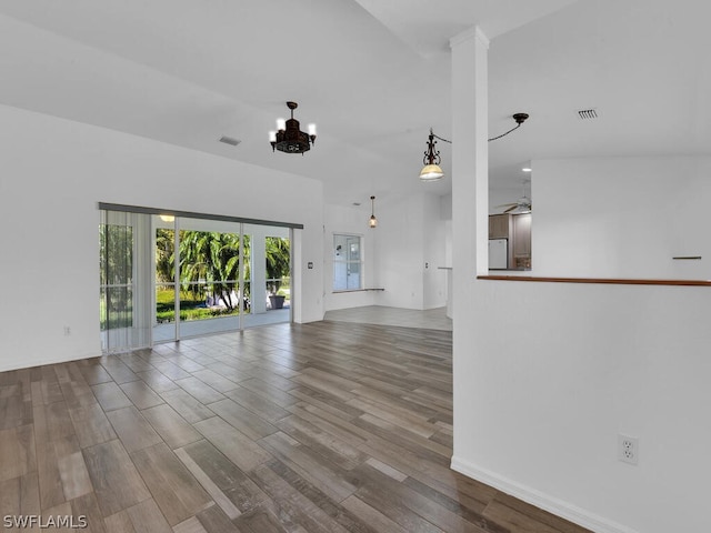 unfurnished living room featuring ceiling fan with notable chandelier and hardwood / wood-style flooring