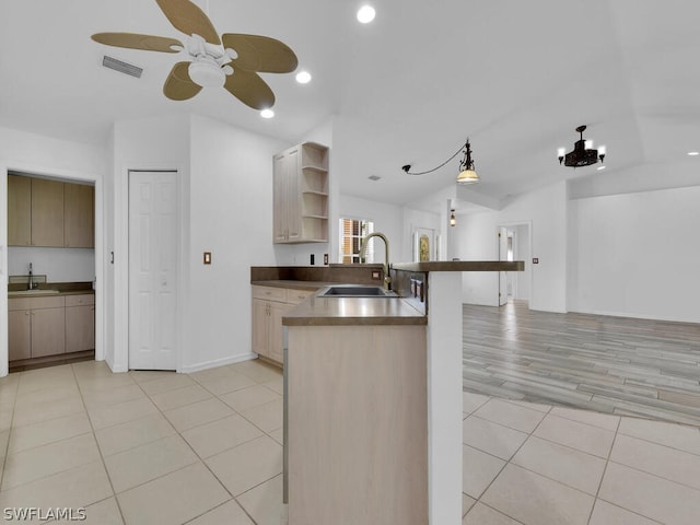 kitchen with ceiling fan with notable chandelier, sink, kitchen peninsula, and light tile floors