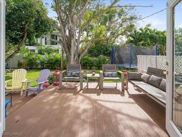 wooden deck featuring a trampoline and an outdoor hangout area