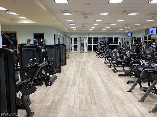 workout area with light hardwood / wood-style floors and a drop ceiling