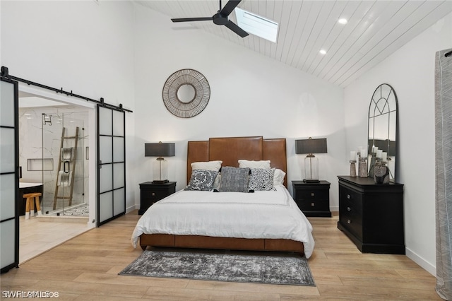 bedroom with a barn door, light hardwood / wood-style flooring, high vaulted ceiling, ensuite bathroom, and wood ceiling