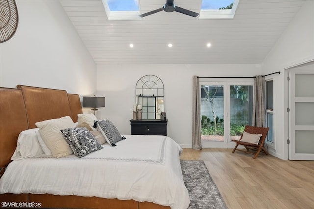 bedroom featuring ceiling fan, light wood-type flooring, high vaulted ceiling, and a skylight