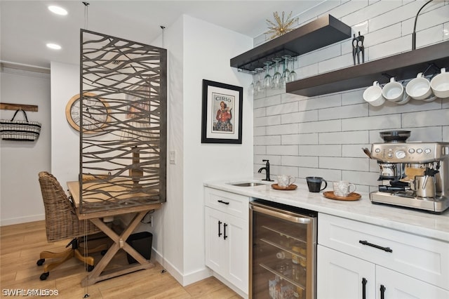 bar featuring white cabinetry, wine cooler, light stone counters, light hardwood / wood-style floors, and decorative backsplash