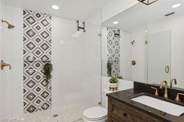 bathroom featuring a tile shower, vanity, toilet, and tile walls