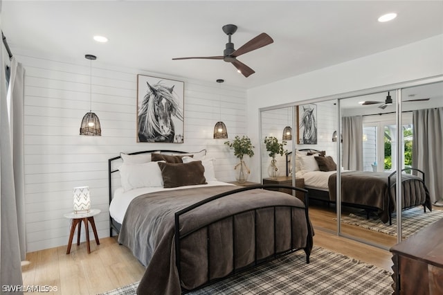 bedroom featuring a closet, ceiling fan, hardwood / wood-style floors, and wood walls