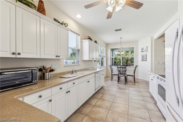 kitchen featuring white cabinets, a wealth of natural light, light tile floors, and decorative light fixtures