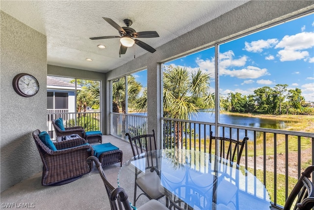 sunroom featuring ceiling fan and a water view