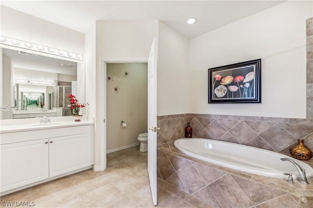 bathroom featuring oversized vanity, tile floors, toilet, and tiled bath