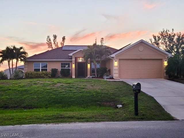 single story home featuring a lawn, solar panels, and a garage