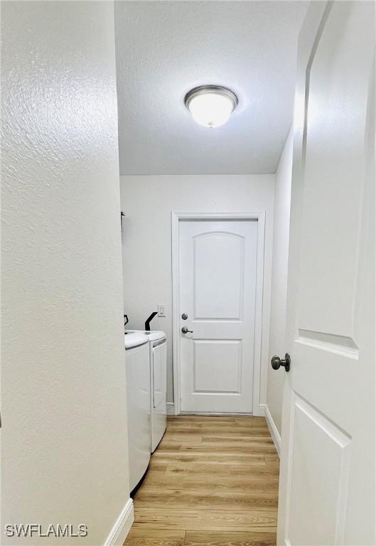 washroom with washing machine and clothes dryer and light hardwood / wood-style floors