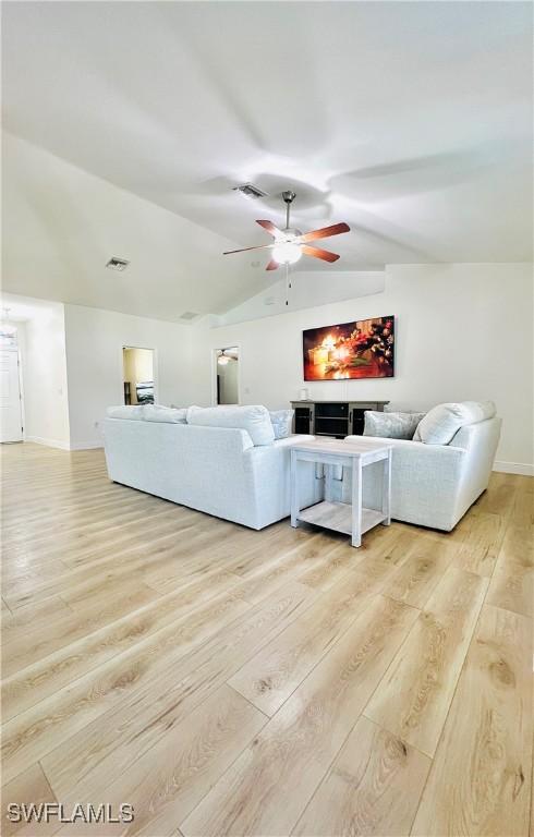 living room with light hardwood / wood-style floors, vaulted ceiling, and ceiling fan