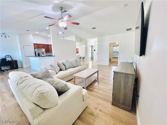 living room featuring ceiling fan, vaulted ceiling, and light wood-type flooring