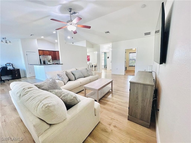 living room with light hardwood / wood-style floors, vaulted ceiling, and ceiling fan