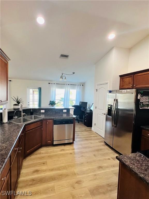 kitchen featuring dark stone counters, sink, light wood-type flooring, and appliances with stainless steel finishes