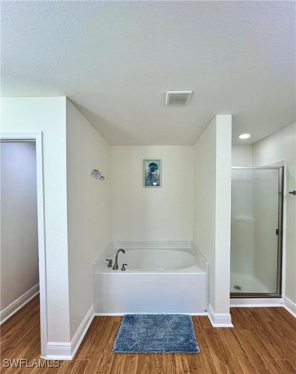 bathroom featuring hardwood / wood-style floors, a textured ceiling, and separate shower and tub