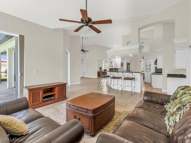 living room with ceiling fan, light hardwood / wood-style floors, and vaulted ceiling