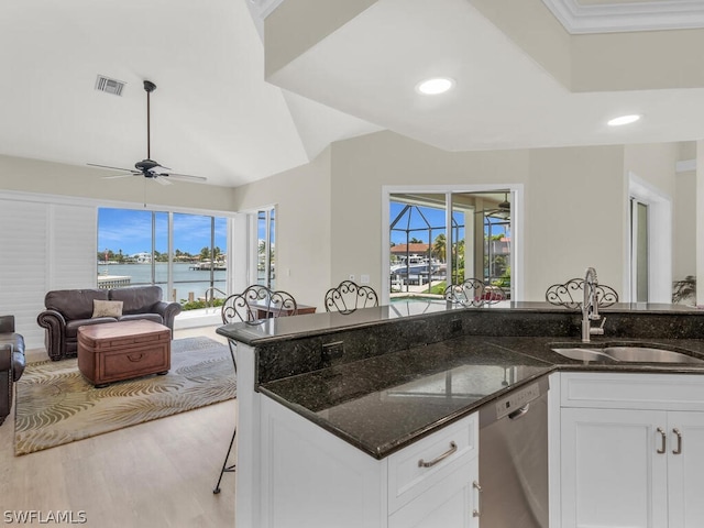 kitchen featuring dishwasher, dark stone counters, white cabinets, a water view, and sink