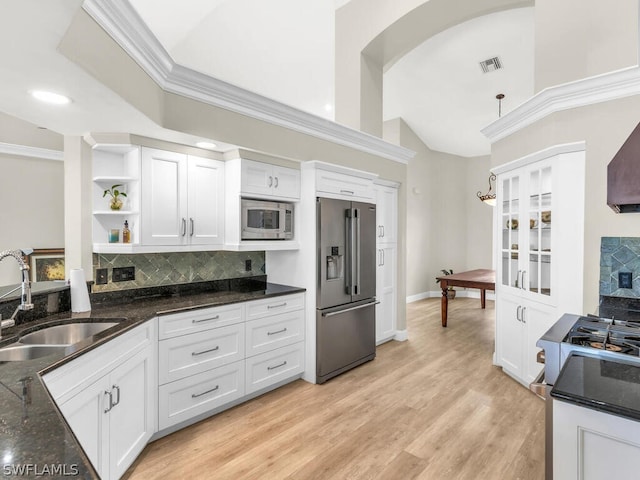 kitchen with appliances with stainless steel finishes, dark stone counters, sink, white cabinets, and hanging light fixtures