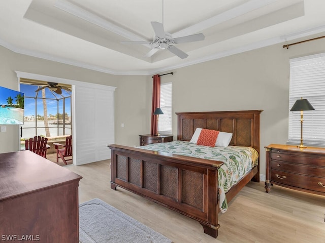 bedroom with a tray ceiling, ceiling fan, and light wood-type flooring