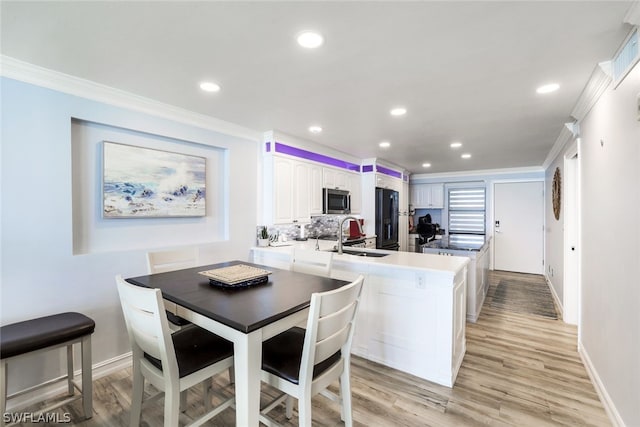 dining room with sink, light hardwood / wood-style floors, and ornamental molding