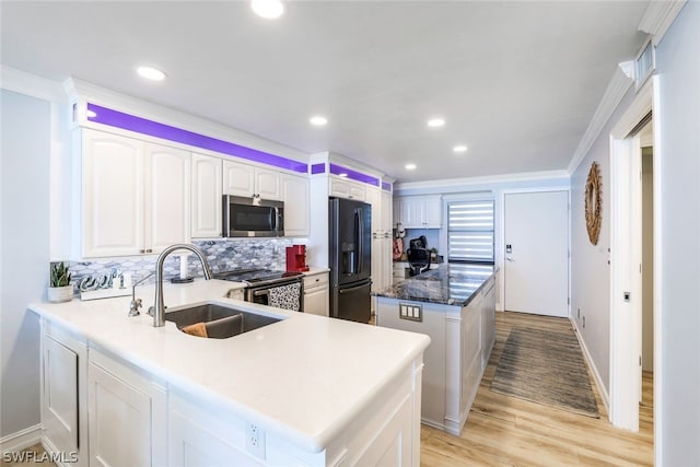 kitchen featuring light wood-type flooring, appliances with stainless steel finishes, kitchen peninsula, backsplash, and sink