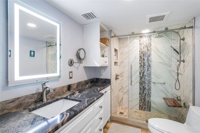 bathroom with an enclosed shower, vanity, and toilet