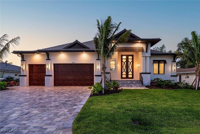 view of front of property with a front lawn, decorative driveway, an attached garage, and stucco siding